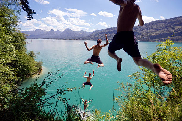 The Jumper Photo sequence of a young man leaping off a cliff into a blue Alpine lake below on a hot summer day. Slight motion blur on young man as he flies through the air. cliff jumping stock pictures, royalty-free photos & images