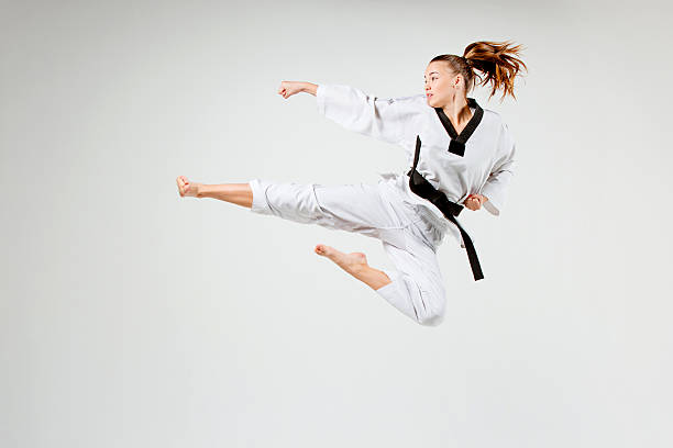 The karate girl with black belt The karate girl in white kimono and black belt training karate over gray background. karate stock pictures, royalty-free photos & images