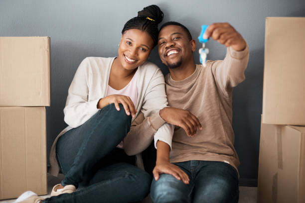 The key to our new dream come true! Portrait of a young couple holding the keys to their new home moving house stock pictures, royalty-free photos & images