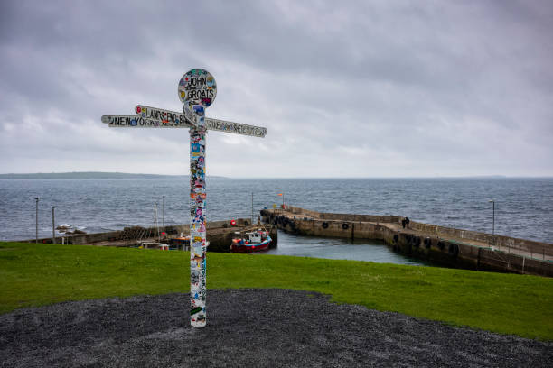 The landmark "Journey's End" signpost at John o' Groats, a popular tourist attraction marking the furthest north on the British mainland, during a cloudy day. stock photo