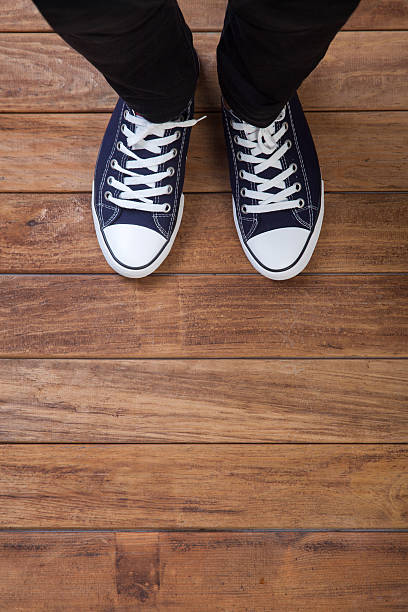 The legs of a man standing on wooden floor stock photo