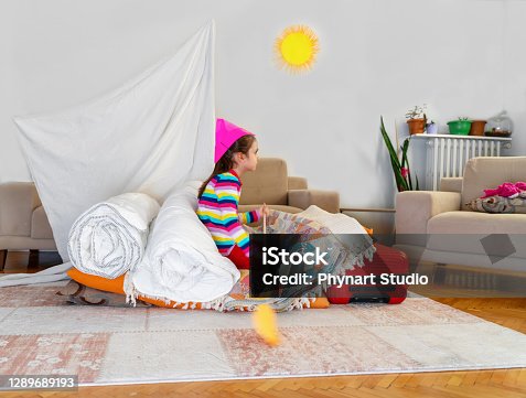 istock The little girl plays a captain and a sailor on a ship she built from torches and pillows. 1289689193