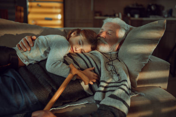 The little granddaughter and grandfather on the sofa stock photo
