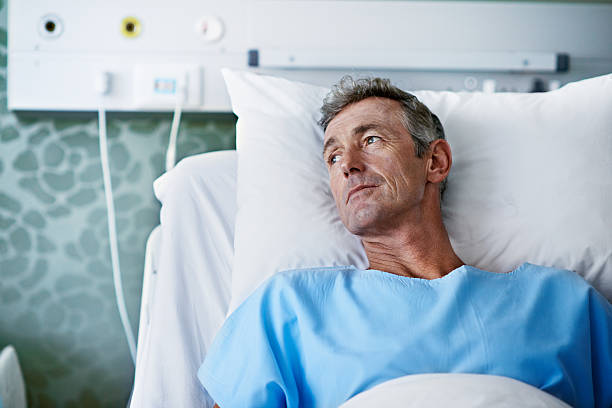 The long hard road to recovery Shot of a sick man lying in a hospital bed patient in hospital bed stock pictures, royalty-free photos & images