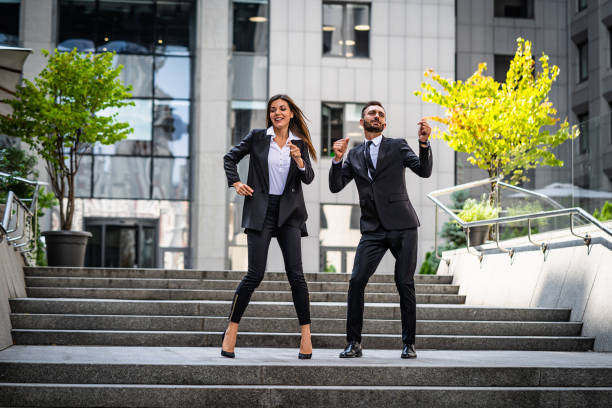 the man and woman in suits dancing near a business center - her happy place is with her team imagens e fotografias de stock