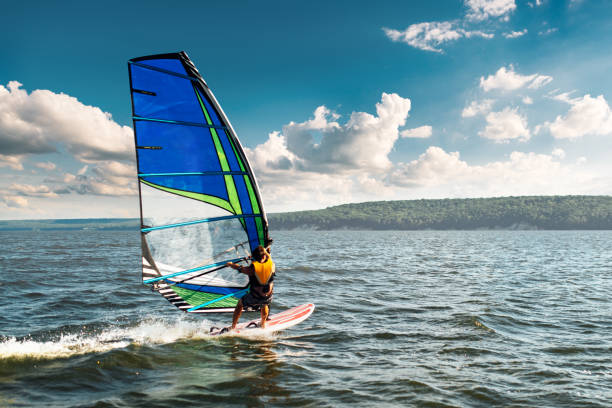 the man athlete rides the windsurf over the waves on lake stock photo