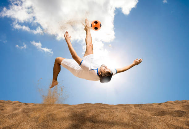 the man footballers are desperately playing beach soccer on sand on a sunny day - futebol de praia imagens e fotografias de stock