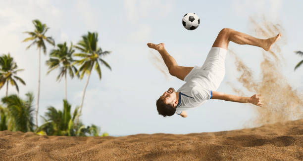 the man footballers are desperately playing beach soccer on sand on a sunny day - futebol de praia imagens e fotografias de stock