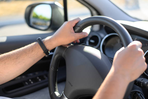The man is driving. Men's hands hold the steering wheel of the car. Selective focus. stock photo