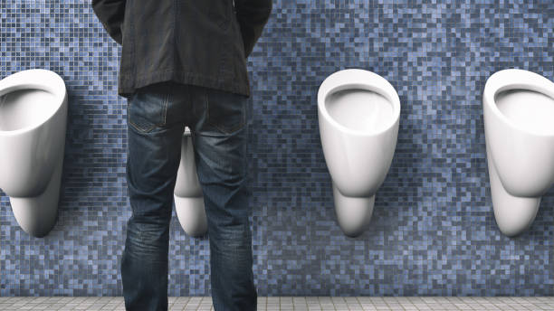 The man is peeing. Back view. Public toilet. Men's health topics. stock photo