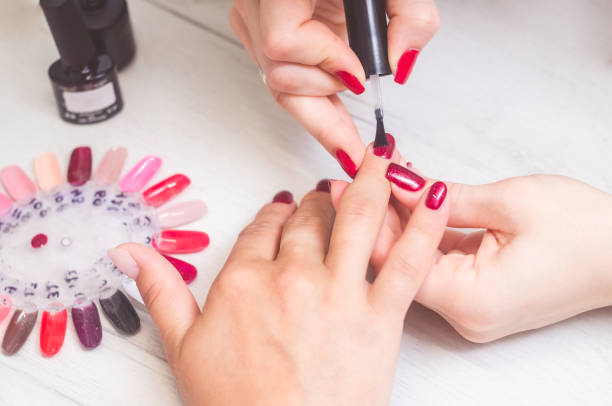 The manicurist paints the nails of women stock photo