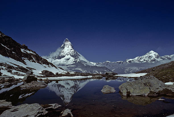 The Matterhorn Reflected in Riffelsee The Matterhorn (14,692') in the Pennine Alps on the border between Switzerland and Italy is probably one of the most recognizable mountains in the world. This reflection of the Matterhorn was taken from Riffelsee above the town of Zermatt in Valais Canton in Switzerland. jeff goulden switzerland stock pictures, royalty-free photos & images