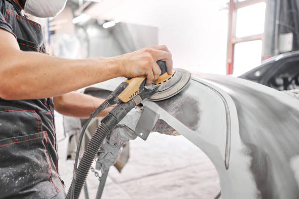 The mechanic works with a grinding tool. Sanding of car elements. Garage painting car service. Repairing car section after the accident. stock photo