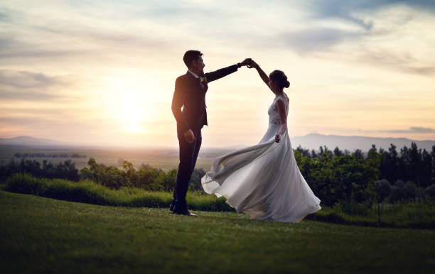 The most beautiful day of their lives Shot of a happy young couple dancing outdoors at sunset on their wedding day bride stock pictures, royalty-free photos & images