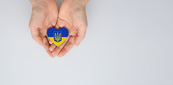 The national flag of ukraine with the coat of arms in female hands. Flat lay, copy space.