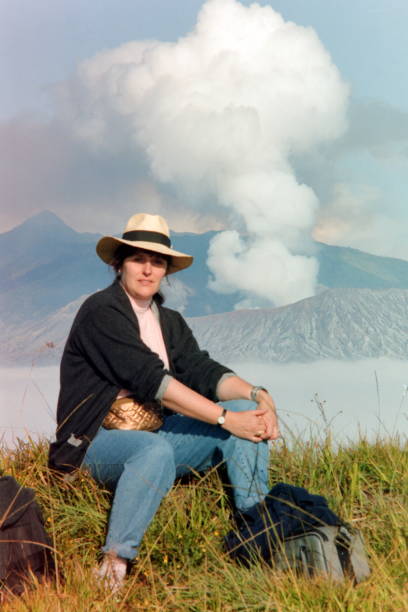 The nineties.  A tourist in front of active volcano Mt Bromo. Java, Indonesia. Mount Bromo natural reserve, East-Java, Indonesia, September 1991. A tourist is sitting at a cliff overlooking the volcano Mt Bromo, which is an active stratovolcano in Indonesia. 1991 stock pictures, royalty-free photos & images