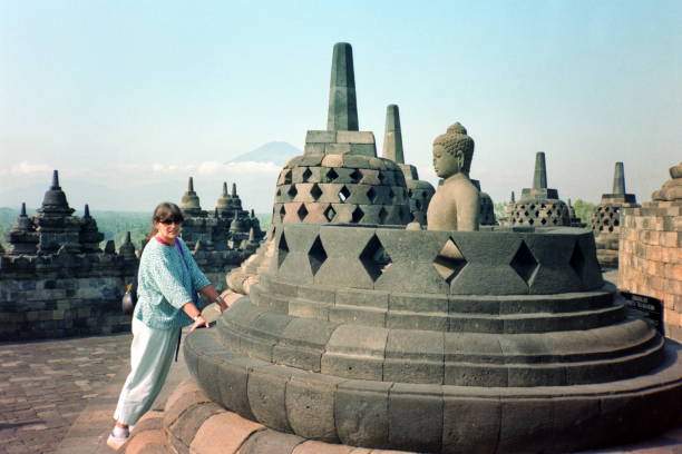 The nineties. A tourist in front of an exposed Buddha in a stupa at Borobudur. Magelang, Indonesia. Magelang, Indonesia - September 17, 1991: A tourist in front of an exposed Buddha in a stupa at the Borobudur Temple, which is considered to be the largest Buddhist temple in the world. This temple "Mahayana" has been restored several times and is a UNESCO World Heritage Site. 1991 stock pictures, royalty-free photos & images