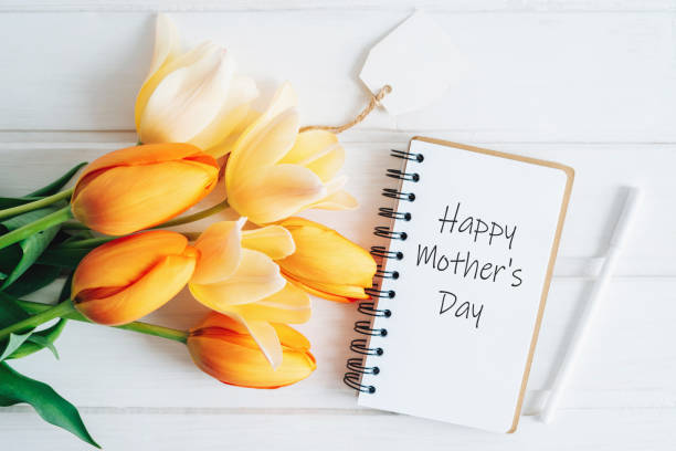 The notebook says Happy Mother's Day The notebook says Happy Mother's Day. A notebook, a pen and a bouquet of tulips lie on a wooden table. A greeting card. quotes about family love stock pictures, royalty-free photos & images