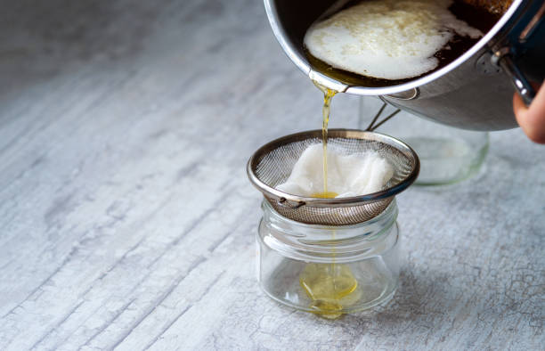 The oil is filtered into a glass jar through a metal sieve The oil is filtered into a glass jar through a metal sieve and cheesecloth. ghee stock pictures, royalty-free photos & images