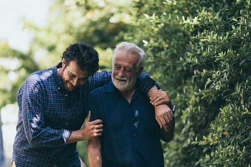 El viejo y su hijo caminan por el parque. Un hombre abraza a su anciano padre. Son felices y sonrientes photo