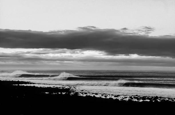 The Perfect Surfing Lineup of Waves in black and white at Raglan, New Zealad stock photo