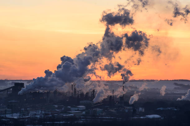 the pipes of the plant throw out toxic smoke at sunset. - kemerovo imagens e fotografias de stock