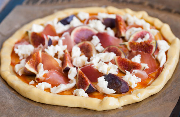 The pizza dough with the ingredients, prosciutto,figs and...