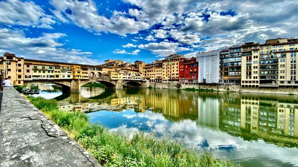the ponte vecchio and reflecting buildings on the arno river, florence, tuscany, italy. stock photo