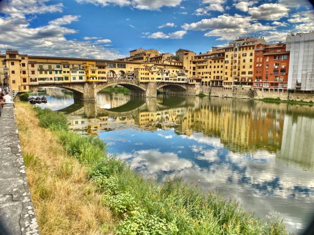the ponte vecchio and reflecting buildings on the arno river, florence, tuscany, italy. stock photo