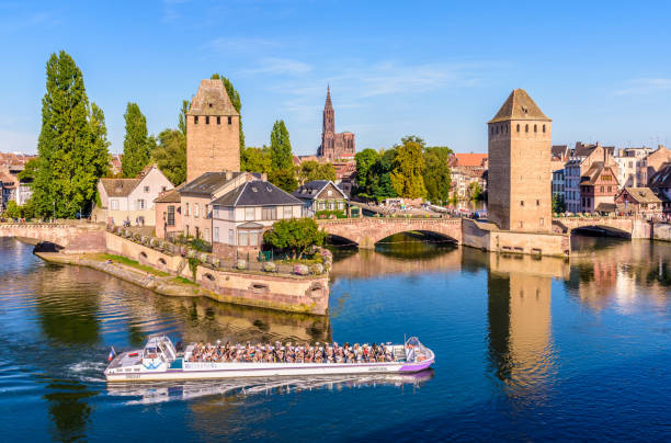 The Ponts Couverts and Notre Dame de Strasbourg cathedral in Strasbourg, France. Strasbourg, France - September 15, 2019: The Ponts Couverts, a set of bridges and towers in the Petite France quarter, and Strasbourg cathedral in the distance with a tour boat cruising on the river. notre dame de strasbourg stock pictures, royalty-free photos & images