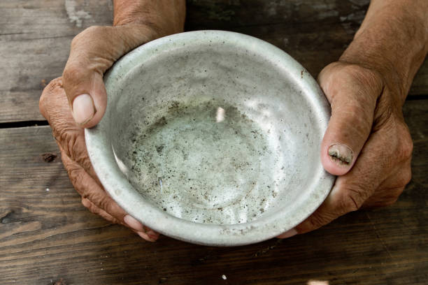 The poor old man's hands hold an empty bowl of beg you for help. The concept of hunger or poverty. Selective focus. Poverty in retirement. Alms stock photo