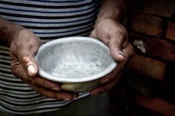 The poor old man's hands hold an empty bowl. The concept of hunger or poverty. Selective focus. Poverty in retirement. Homeless. Alms stock photo