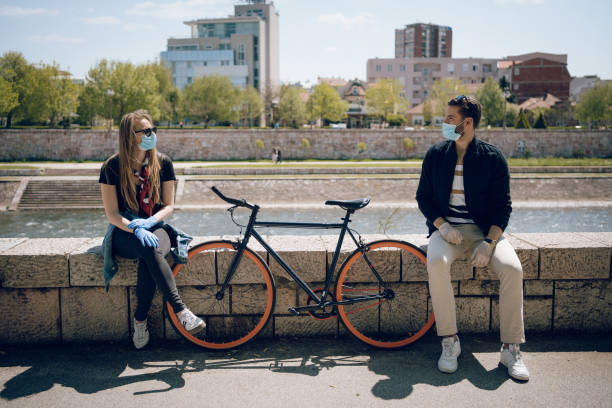 The prescribed measure of social distance is one bicycle Young couple trying to maintain their relationship during a pandemic. They enjoy their love, applying all protection measures and wearing protective masks and gloves. dating stock pictures, royalty-free photos & images