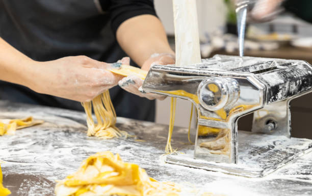 The process of making homemade pasta using a pasta machine. The image can be an illustration of the process of making pasta at home or in a culinary master class. stock photo