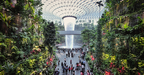 Jewel Changi Airport, Singapore - 5th August, 2019: Visitors tour around the Rain Vortex inside the Jewel area at Changi Airport. It's the world's tallest waterfall at 130 ft in height and surrounded by a four-storey terraced forest. The Jewel complex and waterfall was designed by Moshe Safdie.