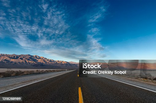 istock The road passing through the desert against the backdrop of mountains. 1318288989