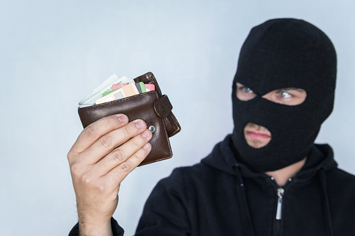 バラクラヴァの強盗は盗まれた財布の中のお金を数えます財布を持ってカメラを見ている黒いマスクの泥棒 札入れのストックフォトや画像を多数ご用意 Istock