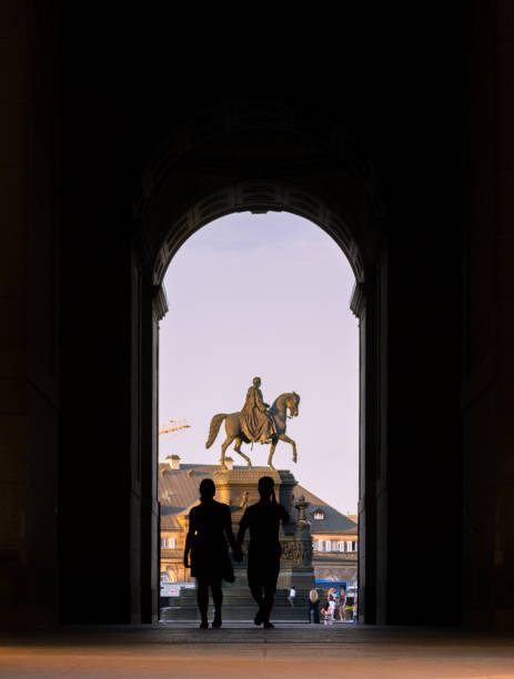 The silhouette of a couple walking hand in hand through an arch Dresden, Germany - July 29, 2018: The silhouette of a couple walking hand in hand through an arch out towards a man on horse sculpture dresden germany stock pictures, royalty-free photos & images