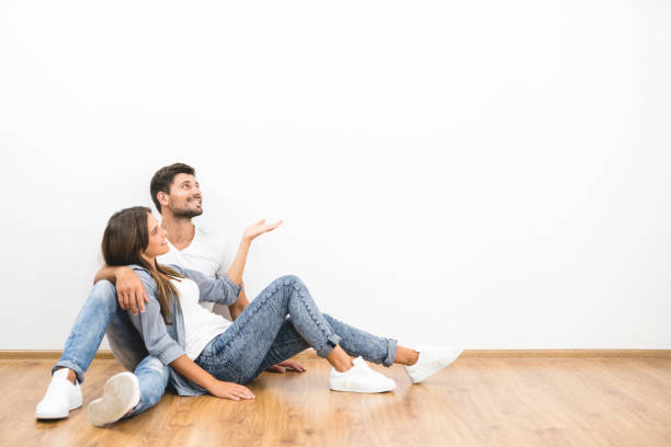 The smile man and woman sit on the background of the empty wall stock photo