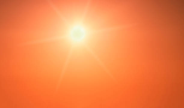 The sun shining brightly in a clear orange sky stock photo