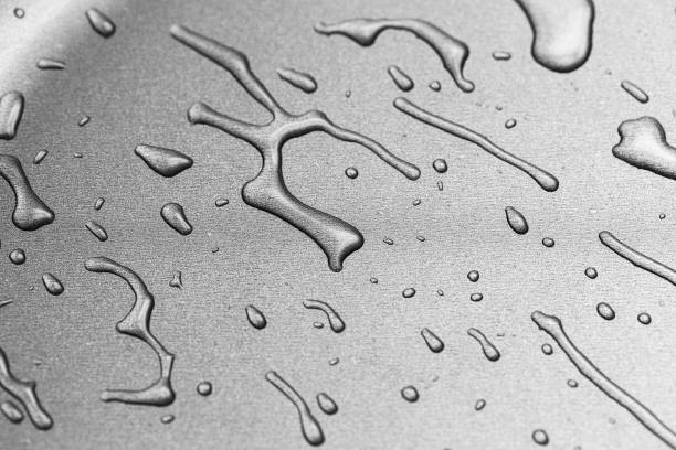 The surface of a frying pan with drops of transparent oil in close-up. Texture of metal cookware for frying The surface of a frying pan with drops of transparent oil. Metal cookware for frying iridium stock pictures, royalty-free photos & images