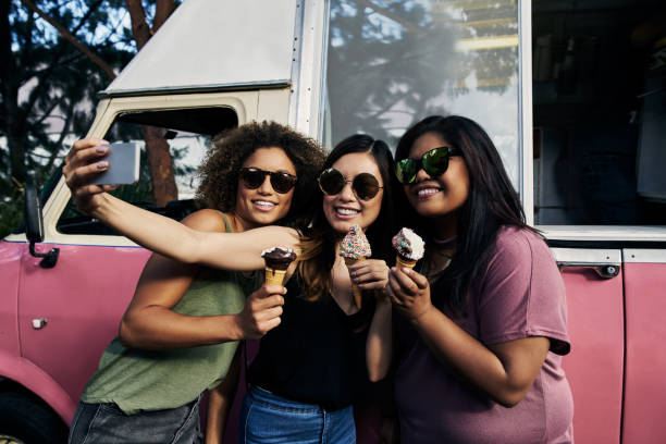 The sweet tooth gang selfie Cropped shot of a group of female friends taking a selfie holding ice cream outside ice cream truck stock pictures, royalty-free photos & images