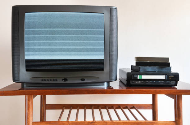 The technology past. Old analog TV and VCR.Old black TV with VCR on the background of wallpaper. The technology past. Old analog TV and VCR.Old black TV with VCR on the background of wallpaper. 90s television set stock pictures, royalty-free photos & images
