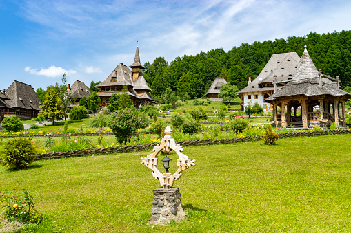 Barsana, Romania - Sep 26, 2018:  Iconic tall wooden spires of church and veranda set in gardens of Barsana Monastery, Maramures region of Romania