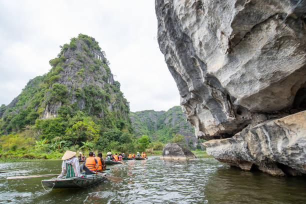 The tourist on cruise local boat, the local people rowing the boat by foots is signature of travel in "Ninh Binh" Hanoi city, Vietnam 11-Jan-2020. stock photo