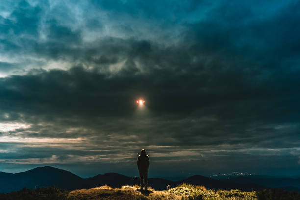 ufo는 산에 서있는 남성에 빛난다 - ufo 뉴스 사진 이미지