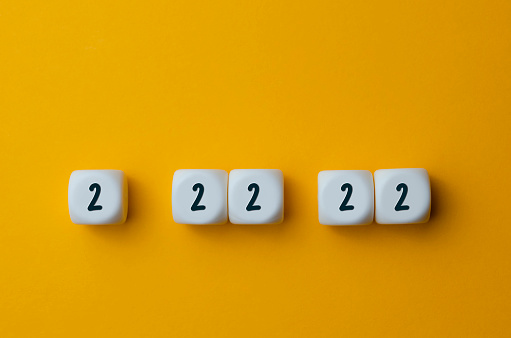 Numbers 2 22 22 on white cubes shapes on yellow background.