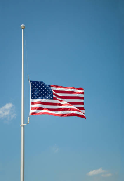 The United States flag at half-mast The United States flag flying at half-mast or half-staff on a flagpole. Blue sky background with copy space. flag at half staff stock pictures, royalty-free photos & images