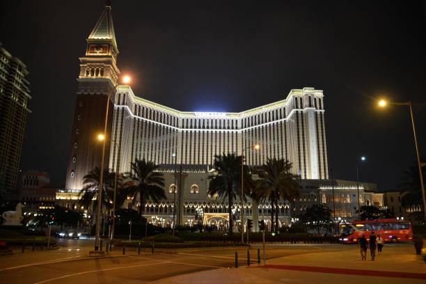 The Venetian by night in Taipa, Macau The Venetian Macao imposing facade by night,. It's the largest casino in the world, and the largest single structure hotel building in Asia. People walking on the street. the venetian macao stock pictures, royalty-free photos & images