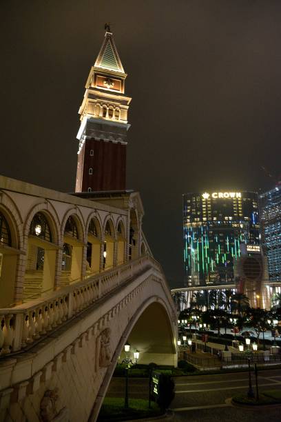The Venetian by night in Taipa, Macau Ponte di Rialto imitation at the Venetian Macao by night,. It's the largest casino in the world, and the largest single structure hotel building in Asia. People walking on the street. the venetian macao stock pictures, royalty-free photos & images
